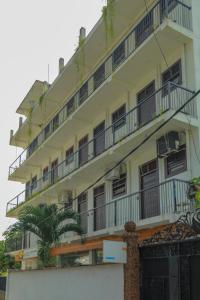 a tall white building with balconies and a palm tree at Traveller's Hotel Hikkaduwa in Hikkaduwa