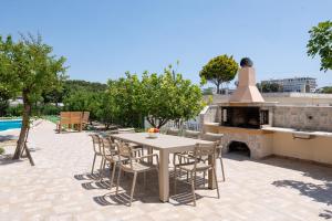 un patio con mesa, sillas y chimenea en Villa Emerald en Asgourou