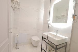 a white bathroom with a sink and a toilet at Olia Residence in Tirana