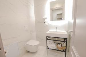 a white bathroom with a toilet and a sink at Olia Residence in Tirana