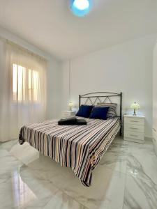a white bedroom with a large bed with blue pillows at SHR043 Nerja Medina Apartamento cerca de Playa Torrecilla in Nerja