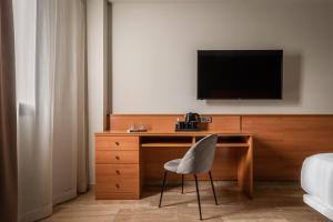 Elle comprend un bureau avec une chaise et une télévision murale. dans l'établissement Hotel SB Express Tarragona, à Tarragone