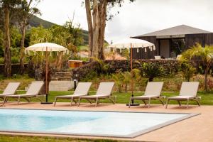 蓬塔德爾加達的住宿－Batalha Golf Villas & Spa，一组椅子和遮阳伞,位于游泳池旁