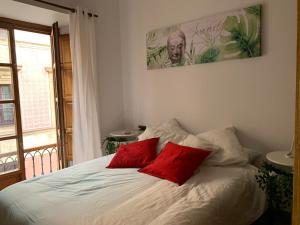 a bedroom with a bed with two red pillows at MyHouseSpain - Acogedor apartamento plaza mayor Gijón 1 in Gijón