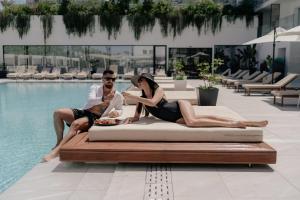 a group of three people sitting next to a swimming pool at At Herbal Boutique Hotel & Spa in Protaras