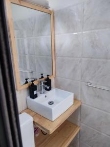 uma casa de banho com um lavatório branco e um espelho. em La residence latinaya em Poponguine