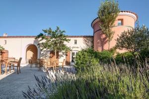 eine Außenterrasse mit Tischen und Stühlen sowie ein Gebäude in der Unterkunft Village Le Rouret - maeva Home - Appartement 2 Pièces 4 Personnes - Sélection MAE-5461 in Grospierres