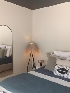 a bedroom with a bed with a lamp and a mirror at Hôtel Les Suites Du Maquis in Bonifacio