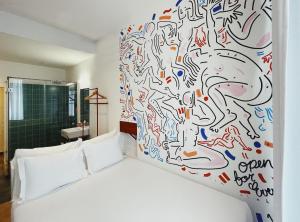 ein Schlafzimmer mit einem weißen Bett und einer Graffiti-Wand in der Unterkunft Esqina Cosmopolitan Lodge in Lissabon