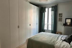 een slaapkamer met een bed met witte kasten en een raam bij Cozy 30 m love nest in Levallois-Perret in Levallois-Perret