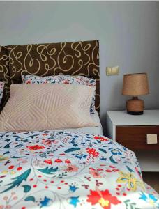 Una cama con un edredón floreado y una lámpara en una mesita de noche. en Sunshine Apartments, en Golem