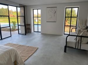 um quarto branco com uma cama, um sofá e janelas em Casa Bianchetti em Costigliole dʼAsti