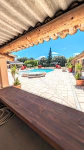 - un banc en bois sur une terrasse avec une piscine dans l'établissement Villa l'Escargolette avec piscine privée, à Carpentras