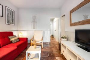 a living room with a red couch and a tv at Park Guell Gaudi 2 bedroom Apartment in Barcelona