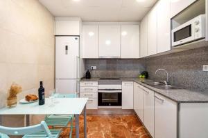 una cocina con armarios blancos y una mesa con sillas. en Park Guell Gaudi 2 bedroom Apartment, en Barcelona