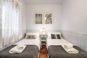 two twin beds in a small room with a side table at Park Guell Gaudi 2 bedroom Apartment in Barcelona