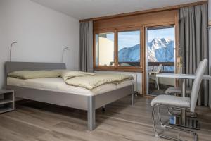 1 dormitorio con cama, mesa y ventana en Ferienwohnungen Zurschmitten, en Riederalp
