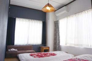 a bedroom with two beds and a couch and windows at 源泉掛け流し温泉付きの宇佐美貸切宿 お宿 喜喜哀楽 Oyado Kikiairaku #IG2 in Ito
