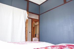 um quarto com uma cama e uma parede azul em 源泉掛け流しの温泉宿 Oyado-Kikiairaku お宿 喜喜哀楽 #IG2 em Ito