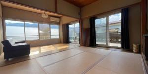 a living room with a chair and large windows at 源泉掛け流し温泉付きの宇佐美貸切宿 お宿 喜喜哀楽 Oyado Kikiairaku #IG2 in Ito