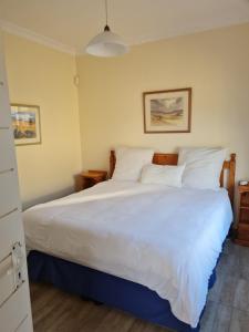 a bedroom with a large bed with white sheets and pillows at Hardman Beach House in Port Edward