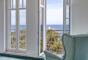 a room with a chair and a view of the ocean at Haus Seeblick Hotel Garni & Ferienwohnungen in Zinnowitz