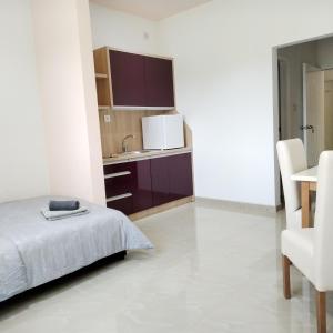 a white bedroom with a bed and a kitchen at Kristal Apartmani - Banja Ždrelo in Ždrelo