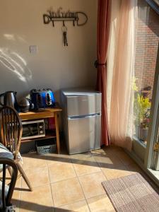 a small refrigerator in a kitchen next to a window at Myrtleberry Studio BnB in Castlemorton