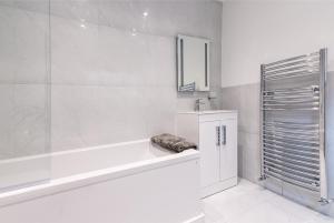 Baño blanco con bañera y lavamanos en Luxury Chester Townhouse with Parking en Chester