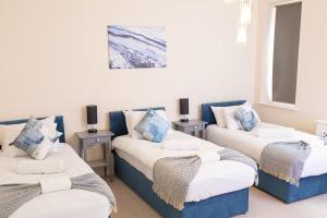 a room with three beds with blue and white pillows at Stunning 3BR Apt Retreat on River Thames l 5Bd2Bth in London