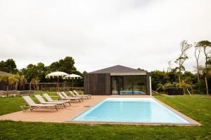 蓬塔德爾加達的住宿－Batalha Golf Villas & Spa，一个带椅子的庭院和房子的游泳池