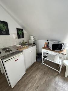 a small kitchen with a stove and a microwave at Le cocon jaune - Studio en hyper centre in Lamballe