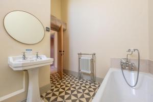 a bathroom with a sink and a tub and a mirror at Peak Hall in Colkirk +50 photos