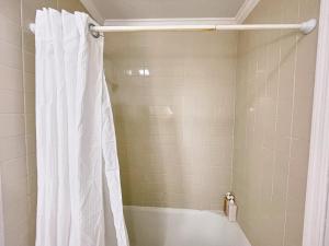 La salle de bains est pourvue d'une douche avec un rideau de douche blanc. dans l'établissement Two Bedrooms - Walk to the Beach!, à Jacksonville Beach