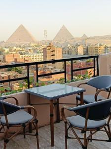 Sneferu Pyramids inn - Full Pyramids View في القاهرة: طاولة وكراسي على شرفة مع الاهرامات