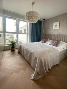 um quarto com uma cama grande e uma janela grande em KOBIELA APARTMENTS Dębowe Tarasy em Katowice