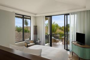 - une chambre avec un lit et un balcon avec une télévision dans l'établissement New World Phu Quoc Resort, à Duong Dong