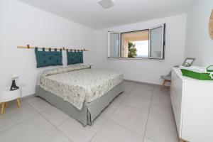 a white bedroom with a bed and a window at Una prua sul mare in Nardò
