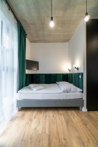 a bedroom with a large bed with green curtains at Apartamenty Silver Place in Szczecin