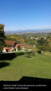 a view of a house in a field of grass at Chalé em Penedo Itatiaia RJ in Itatiaia