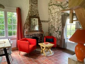 salon z czerwonymi krzesłami i kominkiem w obiekcie Les Cottages d'Orient Premium w mieście Mesnil-Saint-Père