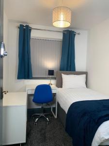 1 dormitorio con 1 cama y escritorio con silla azul en Kunda House Seymour Oldbury en Oldbury