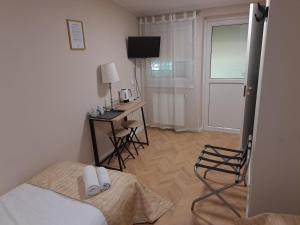 a bedroom with a bed and a desk and a television at Pušelė in Šiauliai