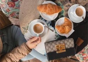 a person is holding a cup of coffee and croissants at Casa Eleonora, balcone con vista e colazione in Assisi