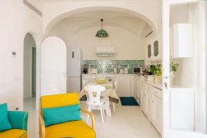a kitchen with white cabinets and a table and chairs at Proprietà Antonio 3 unità indipendenti in Positano