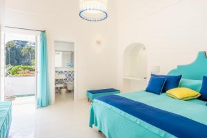 ein weißes Schlafzimmer mit einem blauen Bett und einem Fenster in der Unterkunft Proprietà Antonio 3 unità indipendenti in Positano