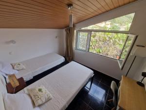 a small room with two beds and a window at Cecília's House in Jardim do Mar