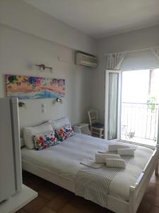 a bedroom with a large white bed with a window at Vetti Rooms in Skiathos