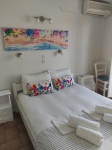 una cama blanca con almohadas y una pintura en la pared en Vetti Rooms, en Skiathos