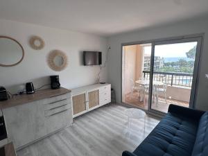 a living room with a couch and a table with a balcony at Appartement T2 avec piscine et vue mer proche plages - FR-1-768-76 in Les Issambres